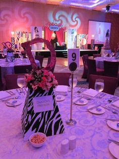 the table is set up for an event with purple lighting and zebra print bags on it