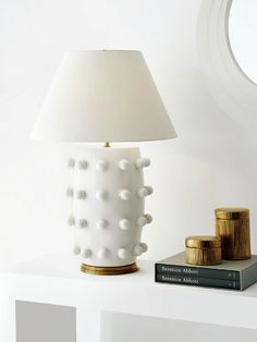 a white lamp sitting on top of a table next to a stack of gold coins