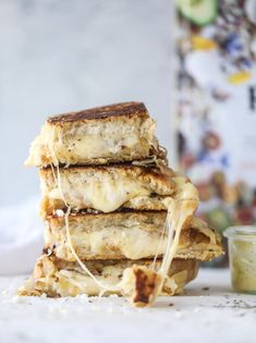 four grilled cheese sandwiches stacked on top of each other with melted cheese covering them