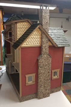 a red house with a green roof and brown shingles on the top is made out of wood