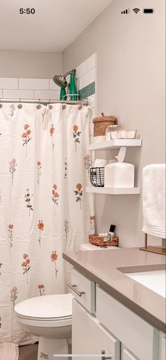 a bathroom with a toilet, sink and shower curtain in it's center area