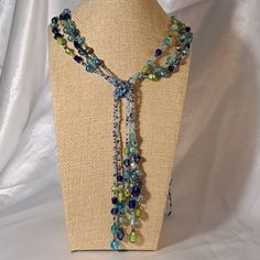 32" Multi Color Green And Blues Make Up This Three Strand Necklace With A Long 6" Tassle. Made With Seed Beads And Larger Mixed Size Glass Beads. Large Silver Tone Metal Closure. This Is A Great Necklace To Wear With A T-Shirt Or A Nice Blouse. Very Adaptable! Handmade Hand-Mde Hand Made Hand Crafted Artisan #2 Blue Beaded Long Necklace With Round Beads, Blue Necklace With 108 Beads For The Beach, Blue Lariat Jewelry For Party, Blue Lariat Jewelry For Beach, Blue Beaded Long Necklace As Gift, Blue Long Necklace With Colorful Beads As A Gift, Adjustable Blue Lariat Necklace As Gift, Elegant Blue Beaded Necklace For Beach, Blue Beaded Lariat Necklace With Round Beads