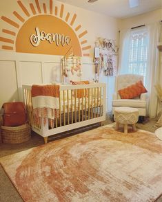 a baby's room with an orange and white rug, sun - themed wall decal, and a gold crib