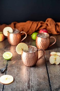 two copper mugs filled with apple cider and garnished with sliced apples