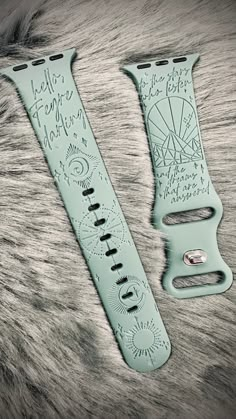 two watch bands with writing on them sitting next to each other in front of a furry surface