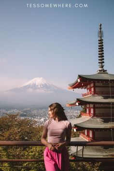 a woman standing in front of a tall building with a mountain in the back ground