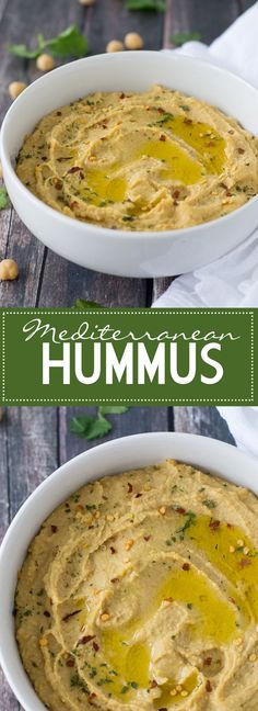 hummus in a white bowl on top of a wooden table with green leaves and nuts