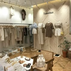 a room filled with lots of clothes on display next to a wooden table and chair