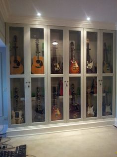 an empty room with guitars on display behind glass doors