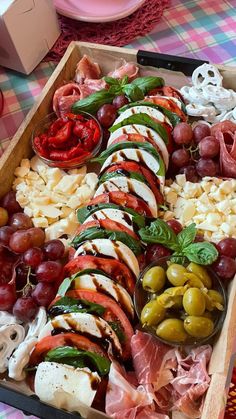 an assortment of meats, cheese and vegetables in a wooden tray on a table