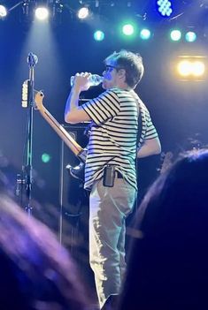 a man standing on top of a stage holding a guitar