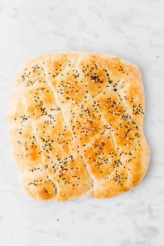 a flat bread with poppy seed sprinkles on a white countertop, ready to be baked