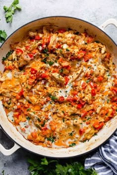 an overhead view of a casserole with chicken, tomatoes and parsley on the side