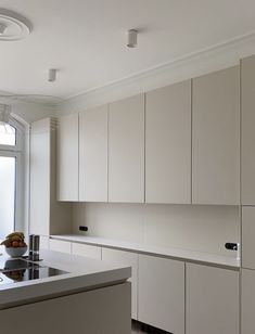 a kitchen with white cabinets and counter tops