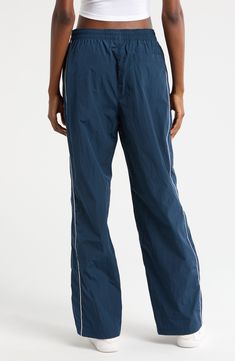 Throwback '70s style and a useful watrer-repellent finish lend style and function to these sporty nylon pants embroidered with a classic Swoosh logo. 30" inseam; 21" leg opening; 13" front rise; 16" back rise (size Medium) Elastic/drawstring waist Side-seam welt pockets; back welt pocket Water repellent 100% nylon Machine wash, tumble dry Imported Nike Functional Parachute Pants For Streetwear, Nike Stretch Nylon Bottoms, Nike Nylon Bottoms With Elastic Waistband, Sporty Nike Nylon Pants, Nike Sporty Nylon Pants, Casual Bottoms With Reflective Details For Outdoor, Casual Outdoor Bottoms With Reflective Details, Full-length Nylon Athleisure Pants, Full Length Nylon Athleisure Pants