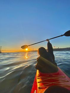 a person in a kayak paddling on the water at sunset