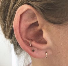 a close up of a person's ear with two piercings on it and one behind the ear