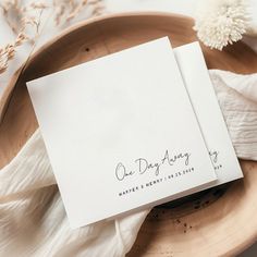 two folded cards sitting on top of a wooden plate