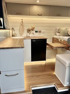 a kitchen with white cabinets and wood flooring next to a living room area that also has couches