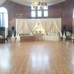 an empty ballroom with white drapes and tables