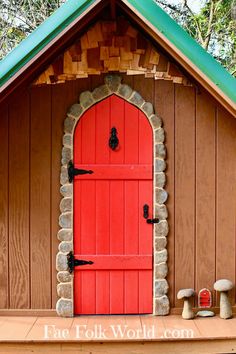 a red door sits in the side of a small building with stone pillars and windows