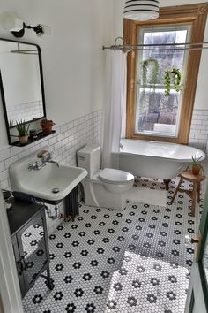 a bathroom with black and white tile flooring next to a bathtub, toilet and sink