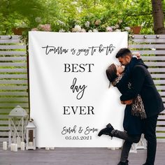 a man and woman kissing in front of a white sign that says best day ever