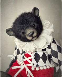 a black teddy bear wearing a red skirt and white shirt with checkerboard on it