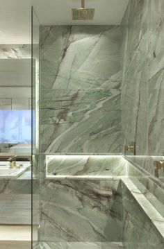 a bathroom with marble walls and flooring, along with a walk in shower area