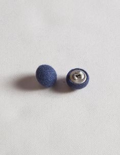 two blue buttons sitting on top of a white surface