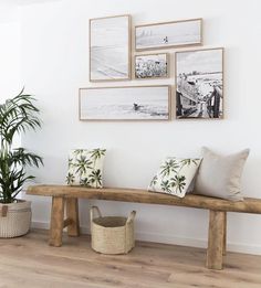 a wooden bench sitting in front of a wall with pictures on the wall above it