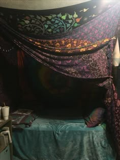 the canopy bed is covered with purple and green fabric