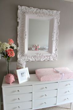 a baby's crib with flowers and a mirror on the wall above it