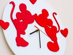 a clock made to look like the silhouettes of mickey and minnie mouse with hearts