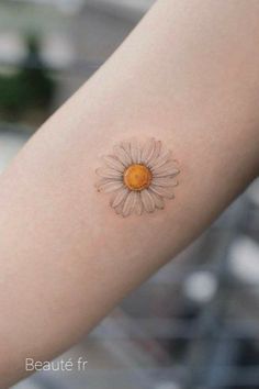 a small daisy tattoo on the arm