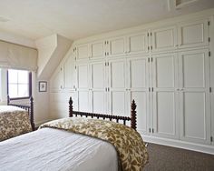 two beds in a room with white cupboards