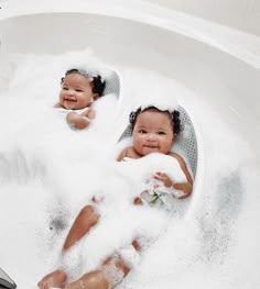 two babies sitting in a bathtub full of foam