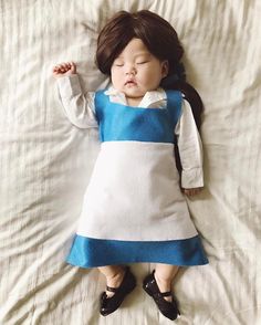 a baby doll that is laying down on a white sheet with its eyes closed and hands behind her head