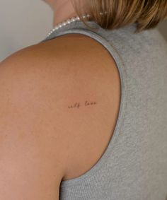 the back of a woman's shoulder with an inscription on it that reads, only love