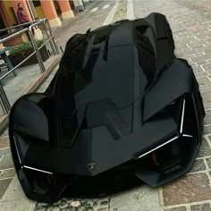 a black sports car parked on the side of a road next to a brick sidewalk