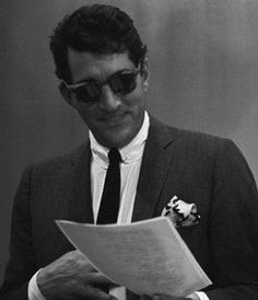 black and white photograph of a man in sunglasses reading a piece of paper with flowers on it