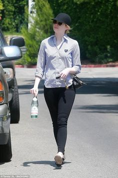 the woman is walking down the street with her hand in her pocket and holding a water bottle