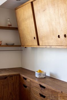 a wooden cabinet and counter in a kitchen with white walls, wood cabinets and drawers