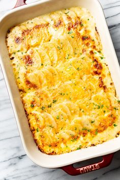 a casserole dish with cheese and parsley in it on a marble surface