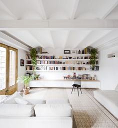 a living room filled with white furniture and bookshelves