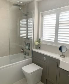 a white toilet sitting in a bathroom next to a bath tub and shower head mounted on a wall