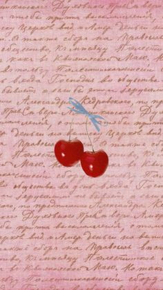 two cherries on a pink background with writing