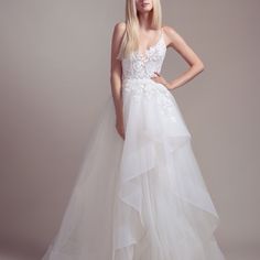 a woman in a white wedding dress posing for the camera with her hands on her hips