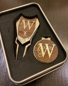 two wooden magnets in a metal box with the letters w and w on them