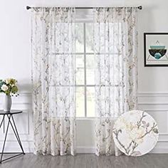 the curtains in this room are white and have floral designs on them, along with a round